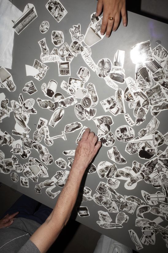 Foto: Größtenteils mit Blitz aufgenommene Eindrücke der Veranstaltung, die entweder Personen um einen langen Tisch mit Klebetattos, im Foyer oder Außenraum der Berlinischen Galerie.