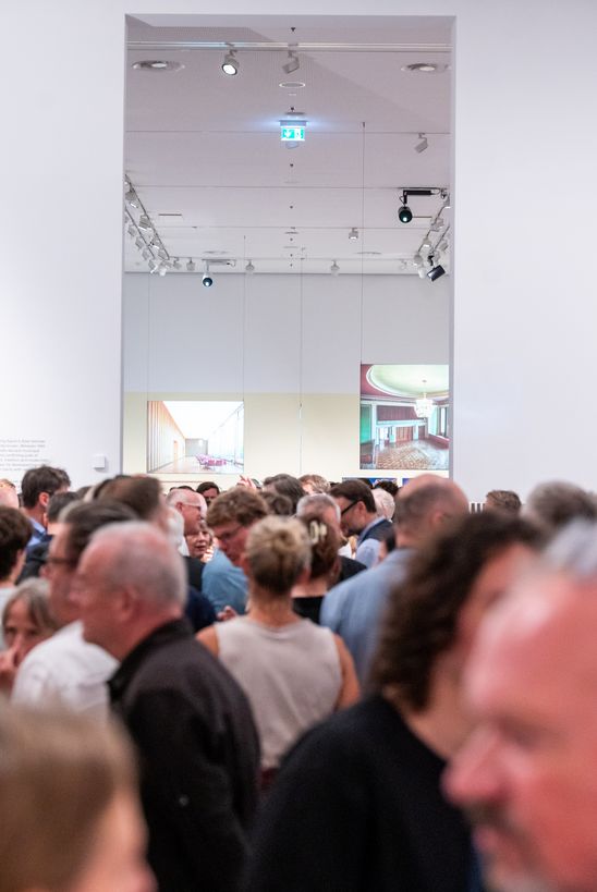 Foto: Eindrücke der Eröffnung, die entweder Menschen in den Ausstellungsräumen oder dem Außenraum der Berlinischen Galerie zeigen.
