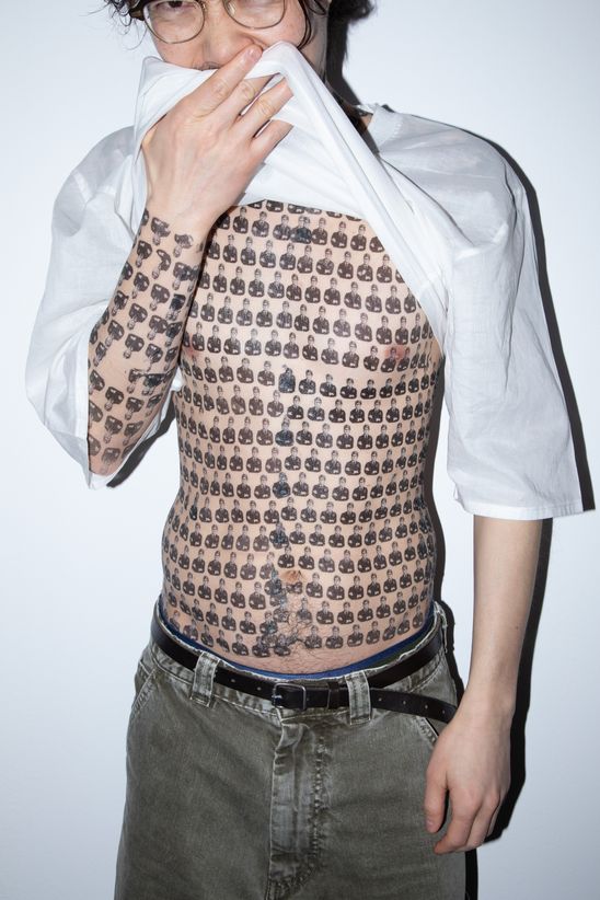 Foto: Hiro mit hochgezogenem weißen Shirt, unter dem der gesamte Oberkörper mit temporären Tattoos von Marc Brandenburg beklebt ist.