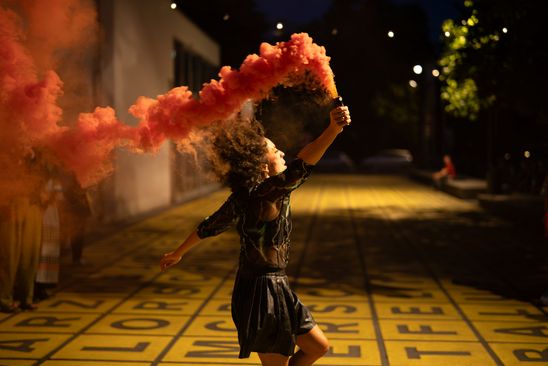 Photo: Mélissa Guex in motion, holding a Bengalo, during her performance, pictured here on the forecourt of the Berlinische Galerie.