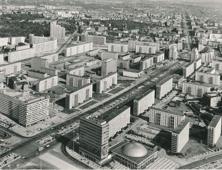 Schwarzweiß-Luftaufnahme der Karl-Marx-Allee und des Alexanderplatzes in Berlin um 1970 mit breiten Straßen, großen Wohnblöcken und weitläufigen Freiflächen