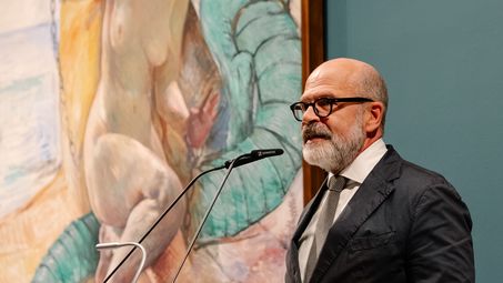 Photo: Thomas Köhler at the lectern in front of a large framed painting by Lovis Corinth.