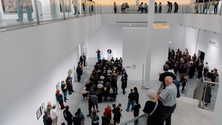 Foto: Eindrücke des Eröffnungsabends, die Menschen entweder bei der Verleihung in der Treppenhalle der Berlinischen Galerie oder zwischen Jeewi Lees Installation im Ausstellungsraum zeigen.