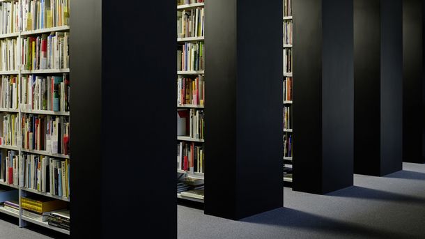 Foto: Parallel angeordnete raumhohe Regale mit Büchern.