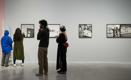 Austellungsansicht „Akinbode Akinbiyi“: Blick in den Ausstellungsraum, in dem vier Personen stehen und sich Schwarz-Weiß-Fotografien von Akinbode Akinbiyi ansehen.