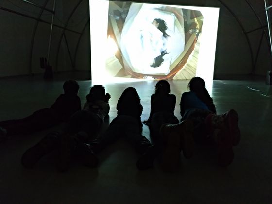 Foto: Kinder sehen sich im Liegen eine Videoinstallation an.