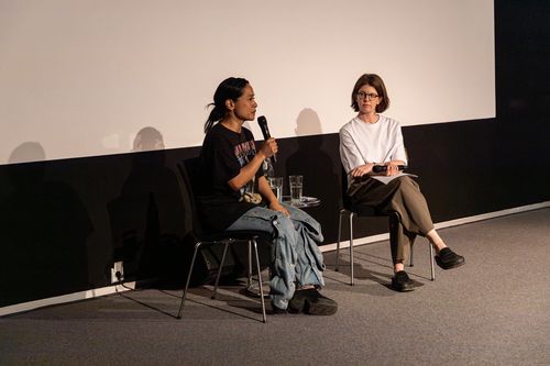 Foto: Stephanie Comilang und Anne Bitterwolf, Kuratorin des Programms, sitzen vor einer weißen Leinwand im Videoraum der Berlinischen Galerie.