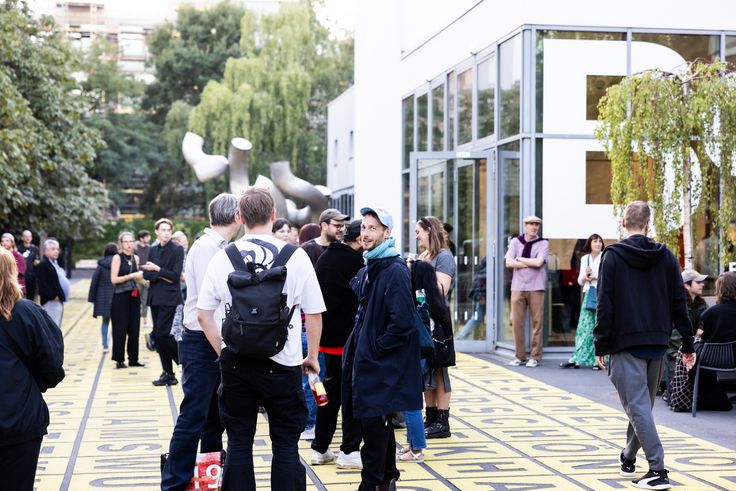 Besucher*innen vor dem Museum Foto: Auf dem Vorplatz der Berlinischen Galerie stehen einige Menschen in kleineren Gruppen zusammen und unterhalten sich miteinander. Eine Person blickt direkt in die Kamera.