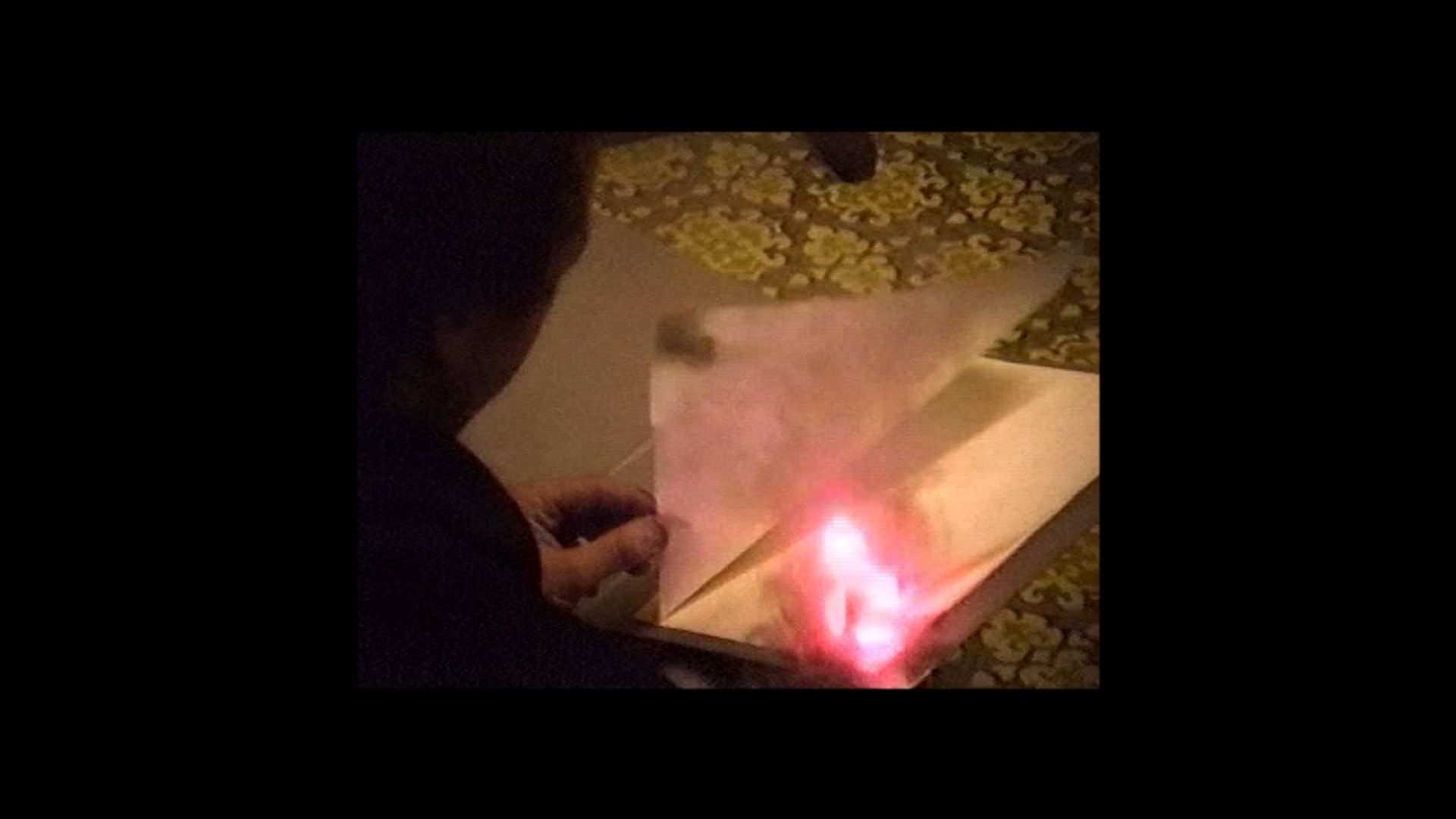 Archivmaterial: Seitenansicht einer nicht erkennbaren Person, die eine Seite eines brennendes Buches umblättert.