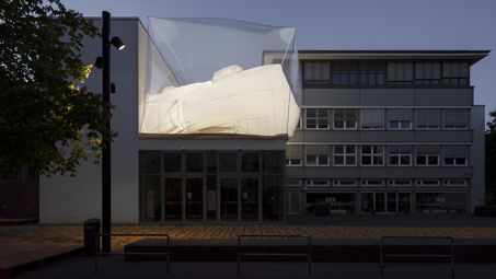 Exterior view of the Berlinische Galerie at dusk with an installation on the roof