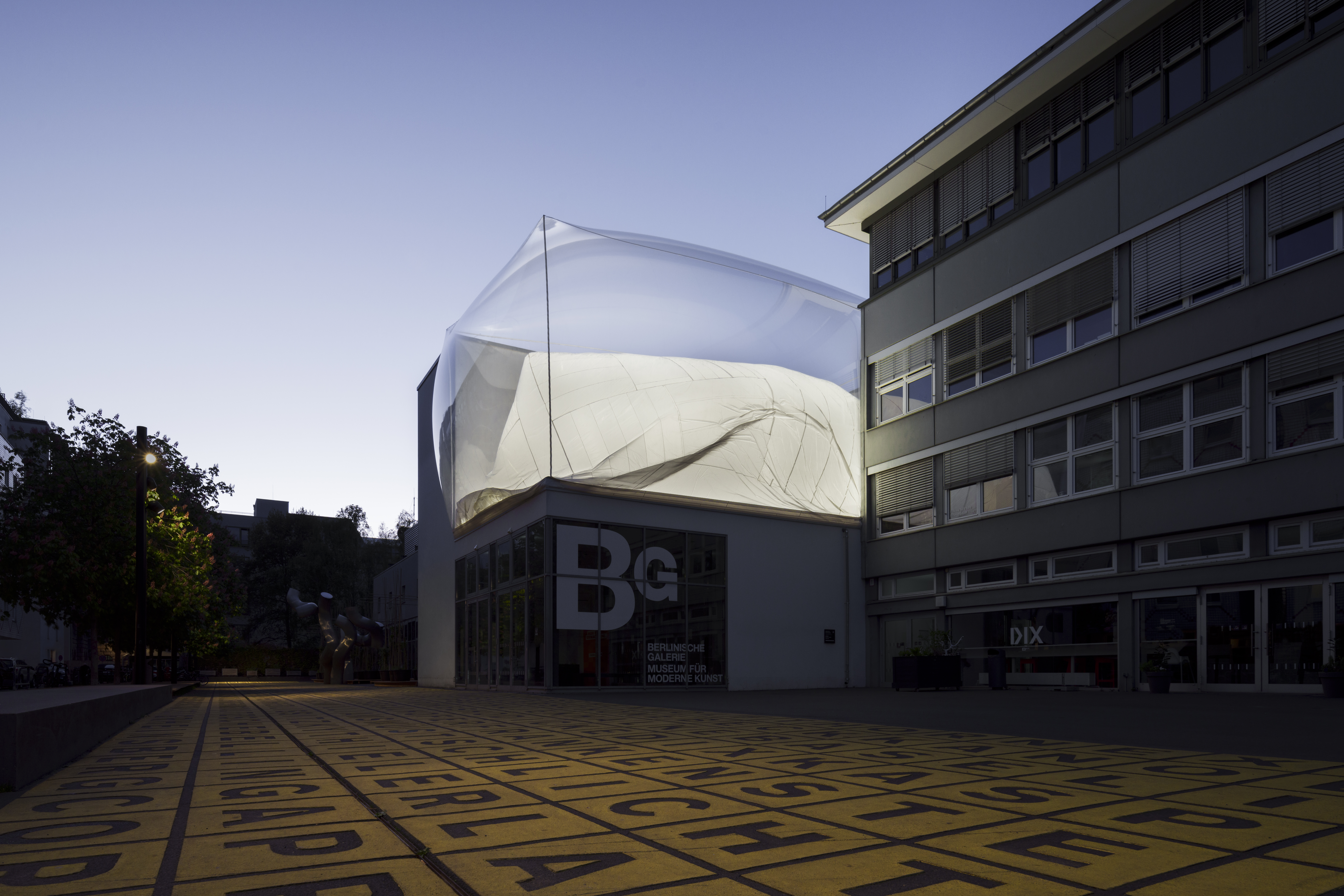 Daniel Hölzl, soft cycles, 2025 Außenansicht der Berlinischen Galerie bei Abenddämmerung mit einer Installation auf dem Dach