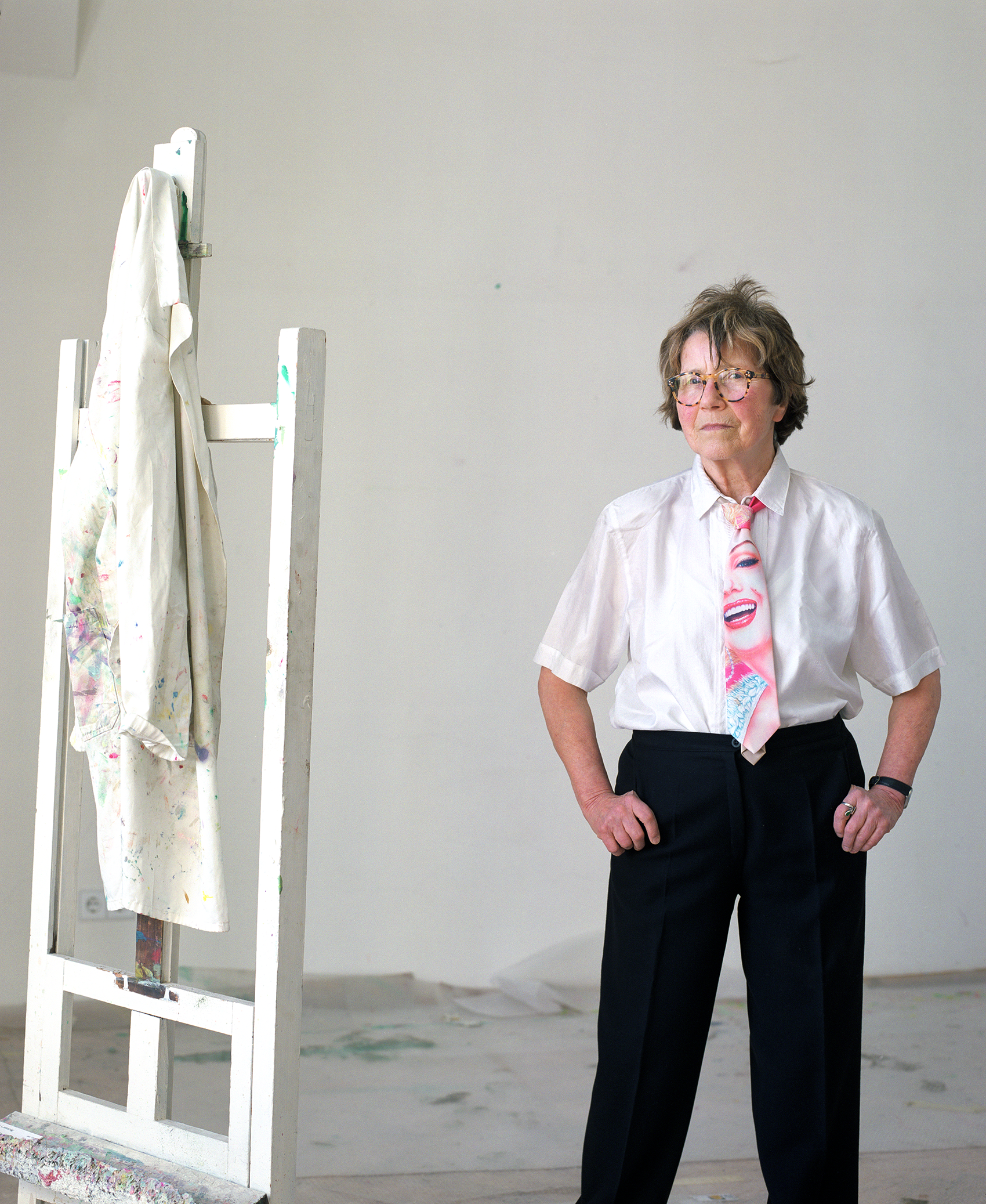 Porträtfoto von Maria Lassnig neben einer weißen Staffelei.