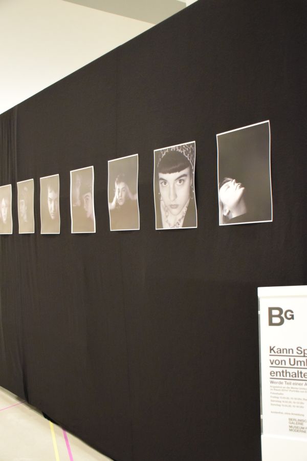Foto: Eine schwarze Wand mit mehreren Foto-Porträts.