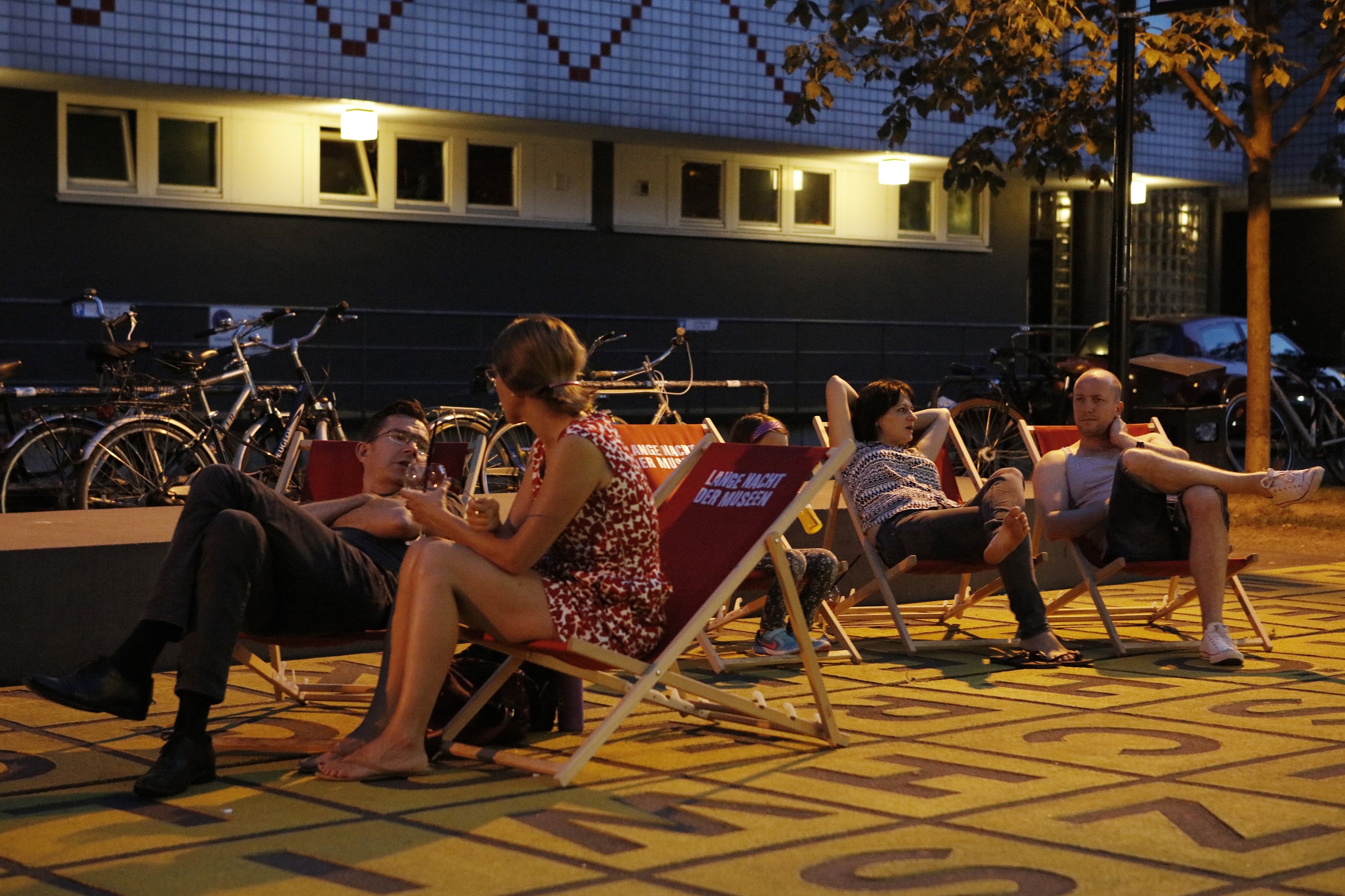 Lange Nacht der Museen Besucher*innen abends in Liegestühlen auf dem Buchstabenfeld